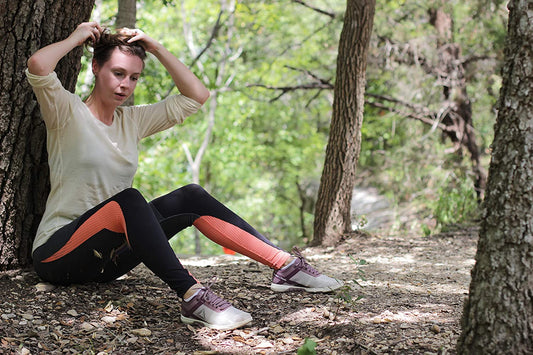 lady taking a break after a walk under a tree wearing roman trail base layer