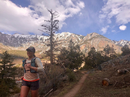 Woman hiking on a trail in winter landscape, wearing roman trail base layer demonstrating tips for Winter Hiking without overheating.