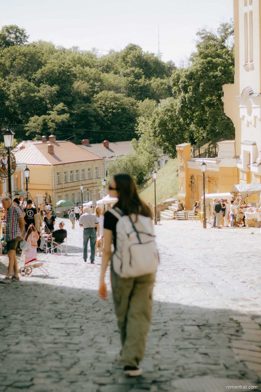 Woman walking a cobblestone city street wearing a white travel daypack