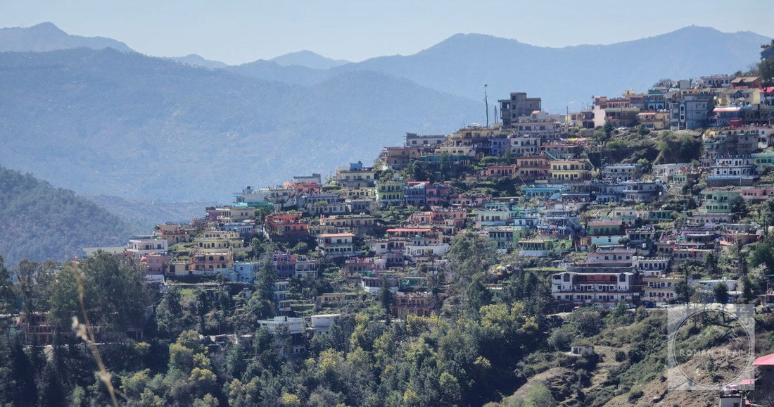 Scenic view of vibrant houses nestled on a hillside in Almora, India surrounded by mountains.