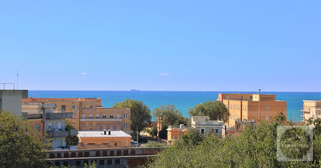 View of Anzio's coastline with vibrant buildings and the Mediterranean Sea under a clear blue sky.