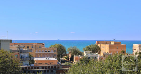 View of Anzio's coastline with vibrant buildings and the Mediterranean Sea under a clear blue sky.