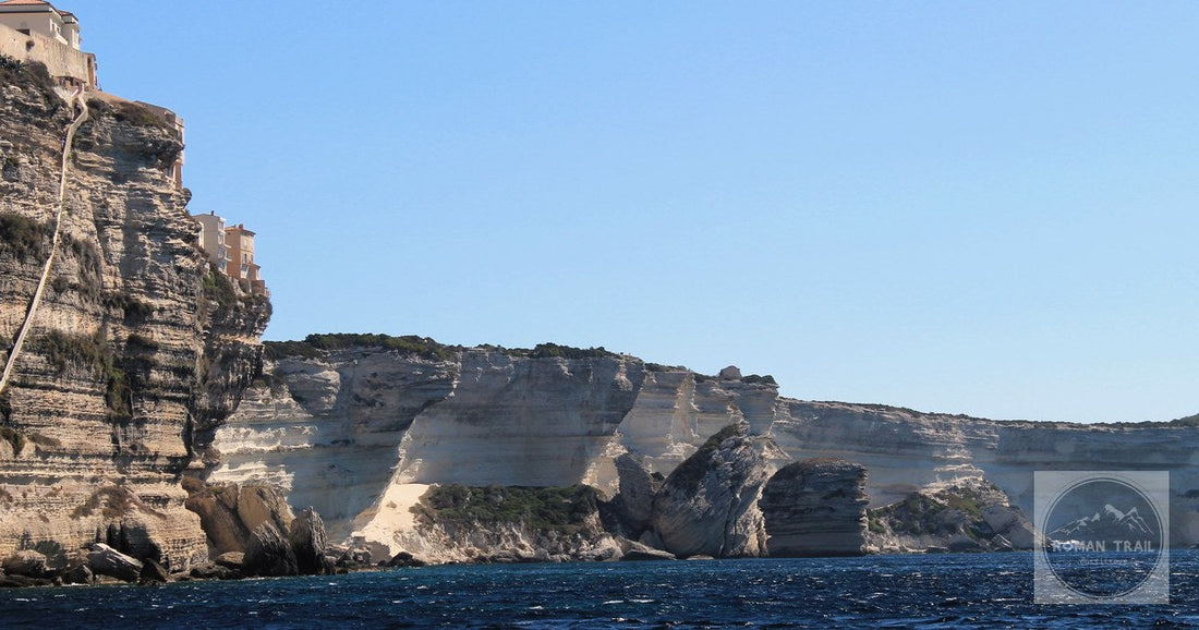 Explore the striking cliffs along Bonifacio's turquoise coastline under a clear blue sky.