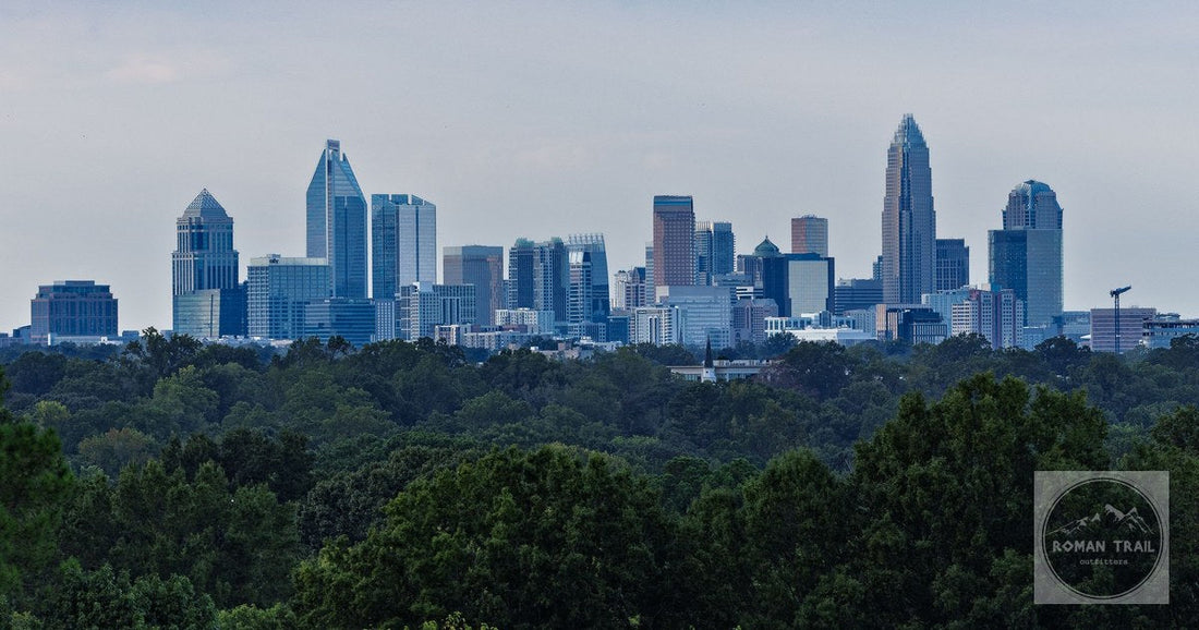 Skyline of Charlotte, NC, featuring modern skyscrapers and lush greenery under a moody sky.