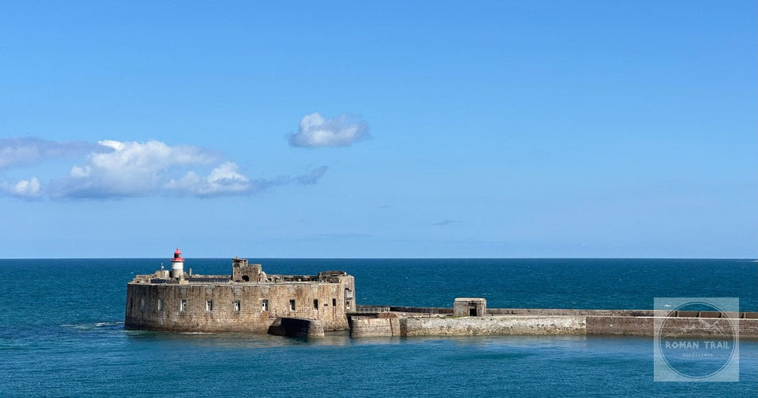 A scenic view of Fort de l'Île Pelée and lighthouse in Cherbourg, France, against a vibrant blue ocean.