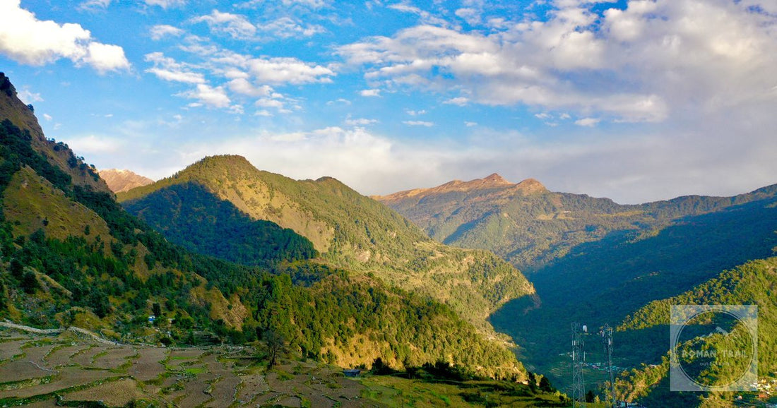 Breathtaking view of mountains and terraced fields in Chopta, India under a bright summer sky.