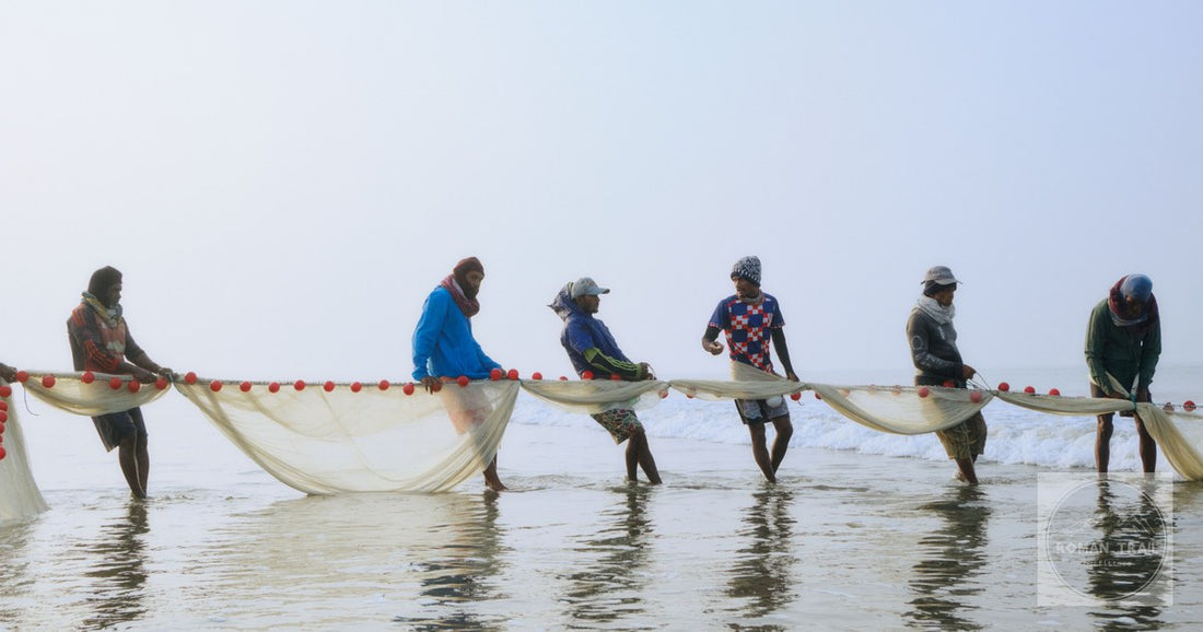Six fishermen pulling nets together in the morning light at Cox's Bazar, Bangladesh