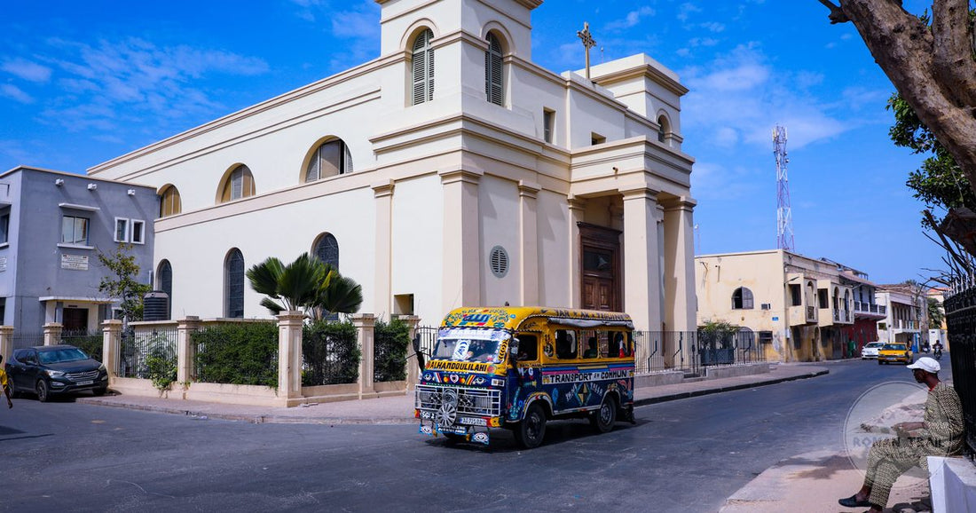 A minibus passing a historic church on a street in Dakar, Senegal