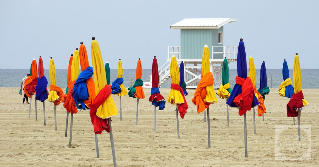 Vibrant beach umbrellas at Deauville beach in Normandie, France, with a tranquil seascape.