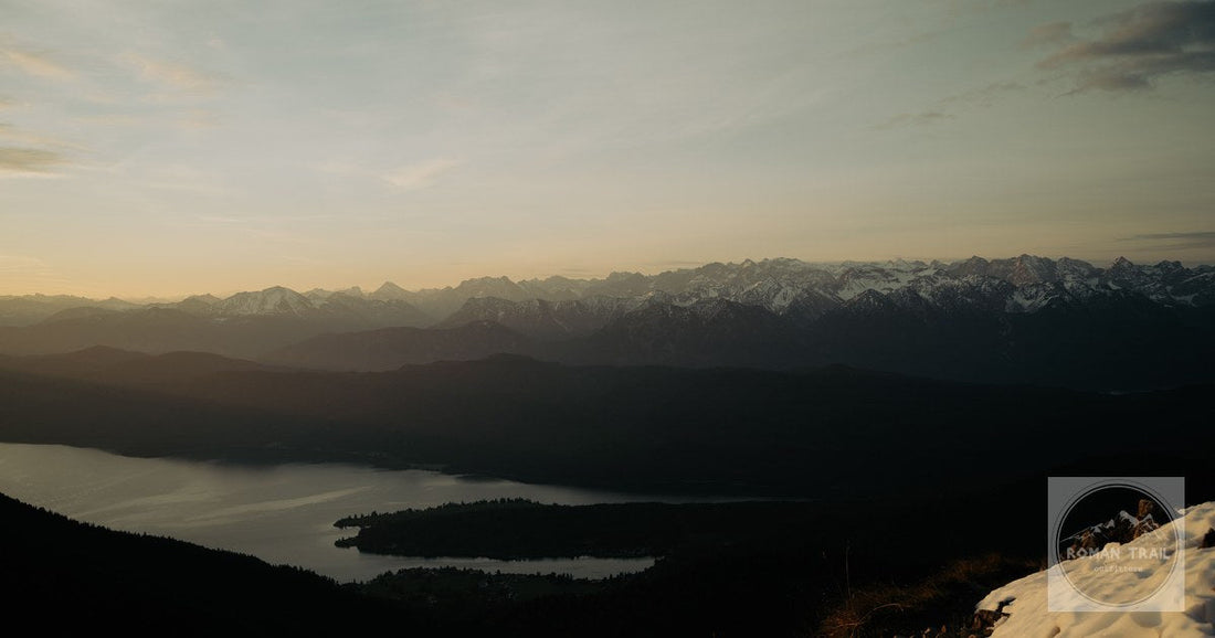 A stunning panoramic view of Garmisch-Partenkirchen's snowy peaks and serene lake at sunrise.