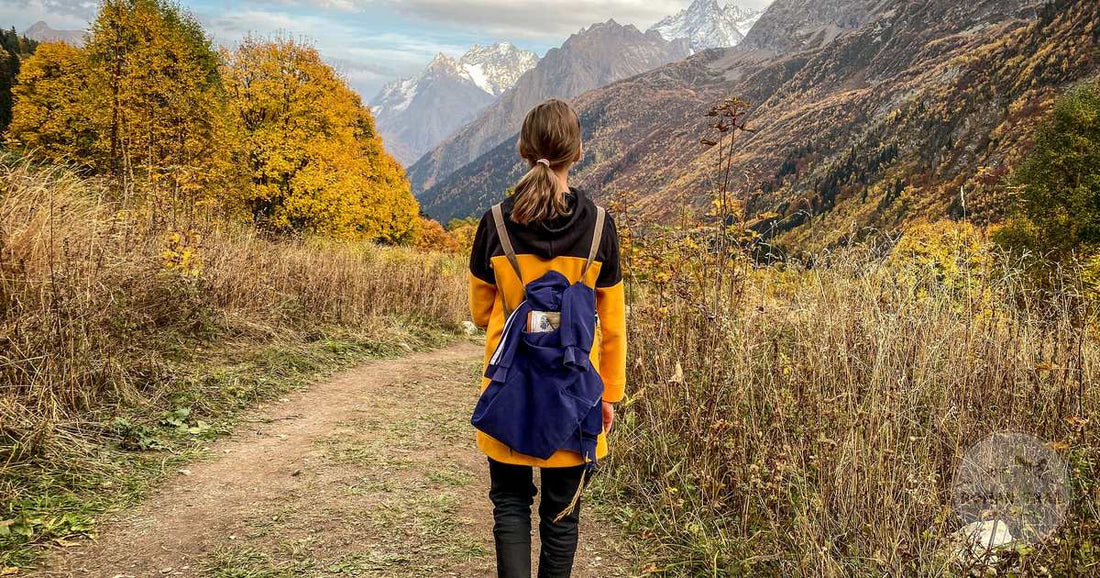 A woman with a backpack hiking through autumn mountain scenery