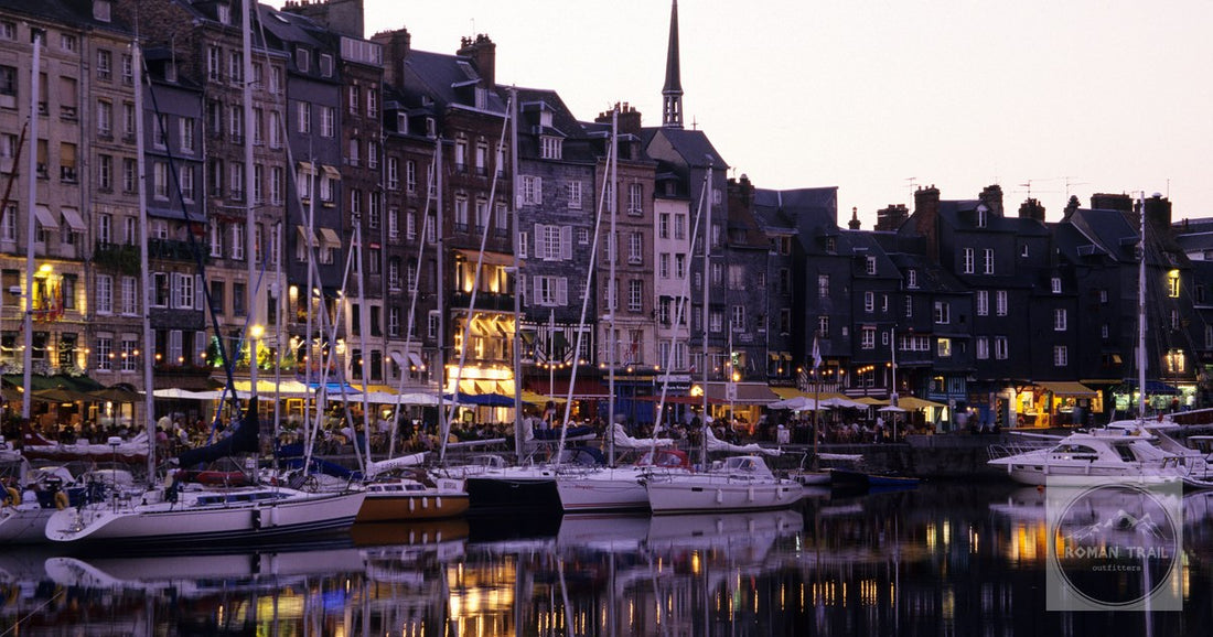 Charming view of Honfleur's illuminated harbor at sunset reflecting on water.