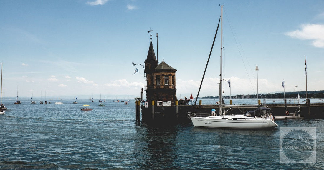 Charming view of sailboats and the iconic harbor tower in Konstanz, Germany on a sunny day.