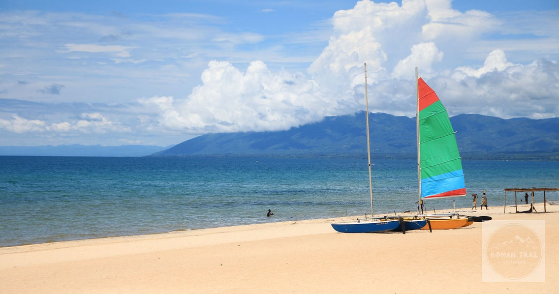 Painted sailboats drawn up on a Lake Malawi beach with mountains behind, Malawi