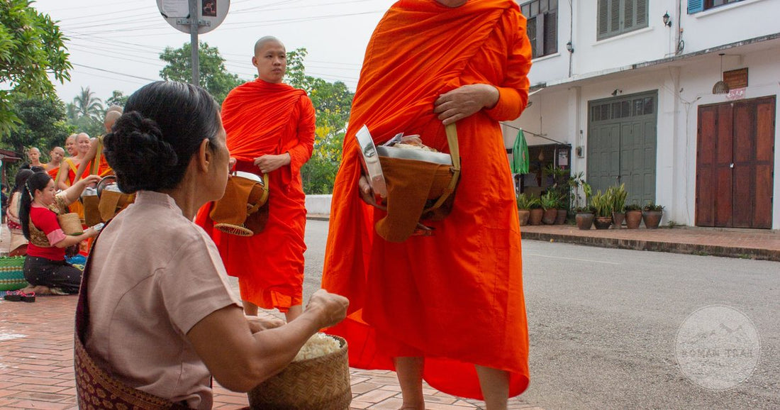 Saffron robed monks receiving alms at dawn in Luang Prabang, Luang Prabang packing list for women by Roman Trail Outfitters