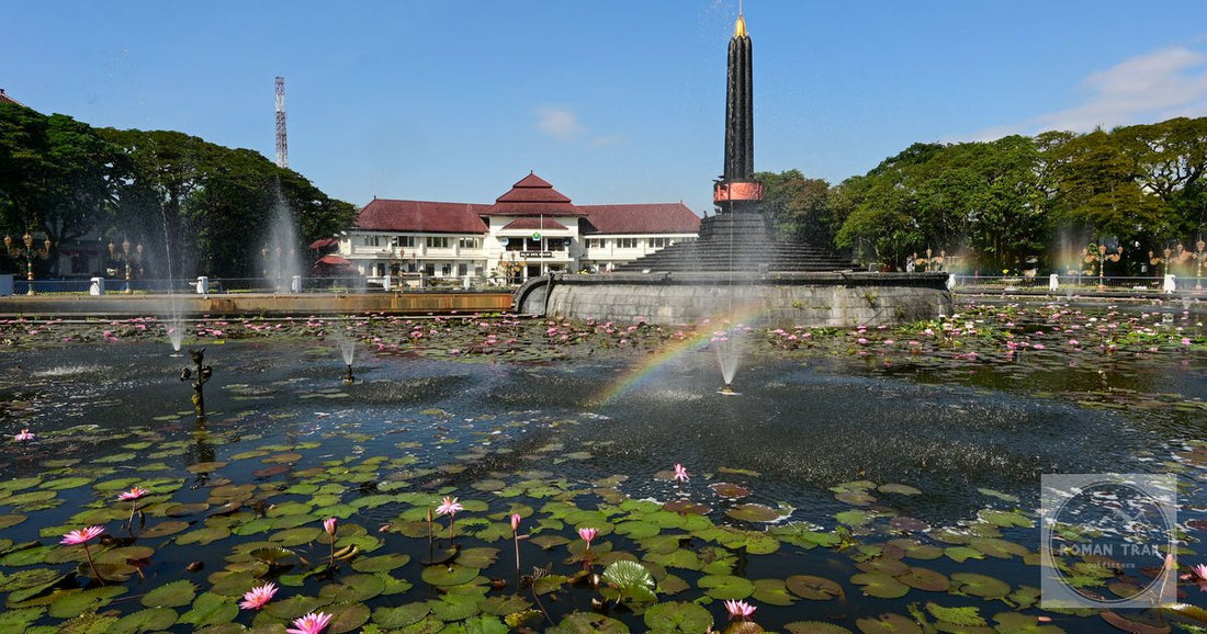 Scenic view of Tugu Malang Monument with pink water lilies in a vibrant pond under a clear sky.
