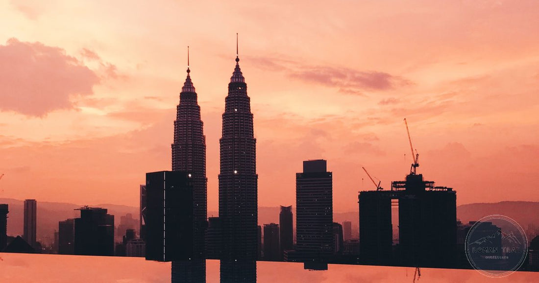Petronas Twin Towers silhouetted against an orange sunset sky, reflected in an infinity pool, Kuala Lumpur