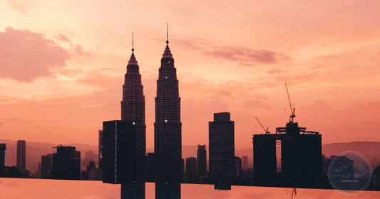 Petronas Twin Towers silhouetted against an orange sunset sky, reflected in an infinity pool, Kuala Lumpur