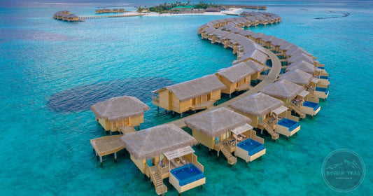 Overwater bungalows curving across a turquoise lagoon at golden hour in the Maldives