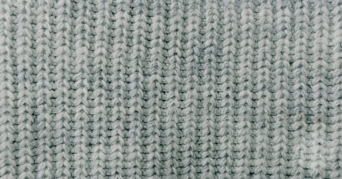 Close detail of grey knitted woollen fabric showing the stitch structure