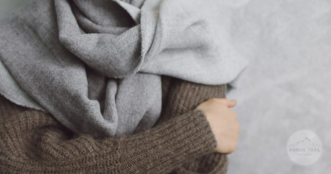 A close view of a grey scarf over a brown knitted wool sweater