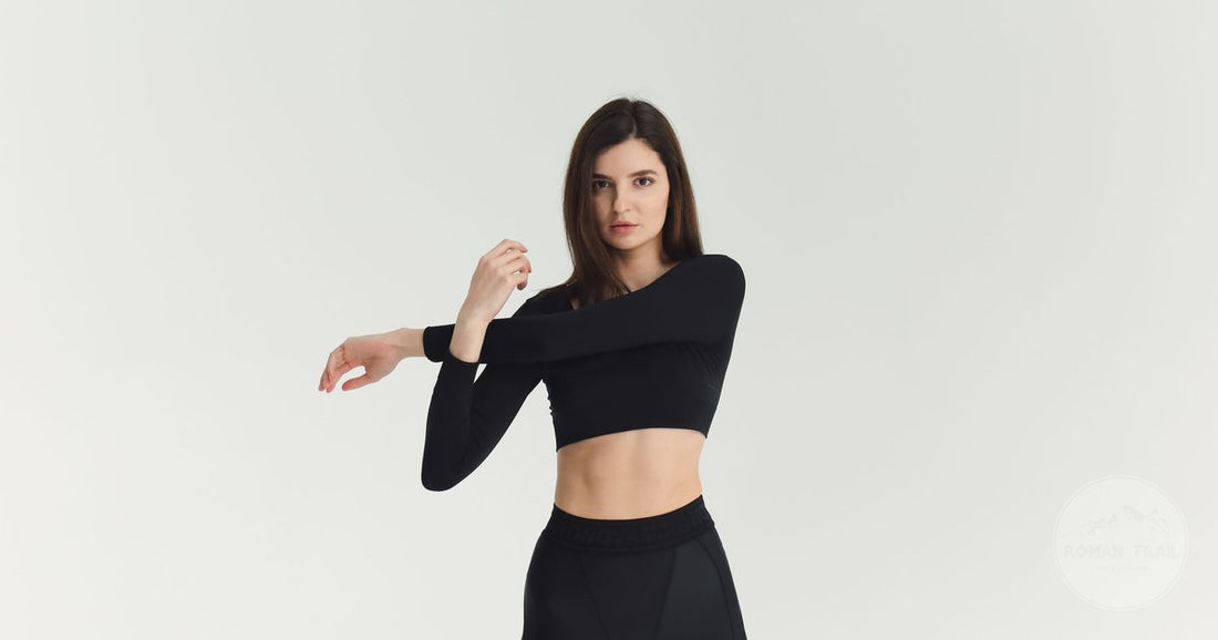 A woman in a close fitting black base layer top stretching indoors