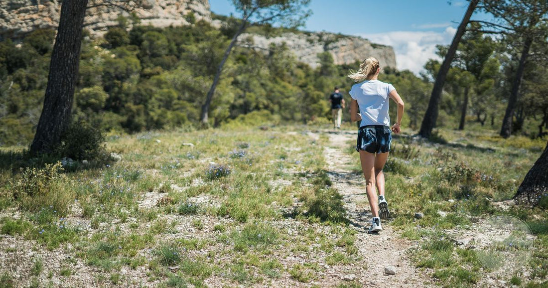 A woman running on a mountain trail in summer