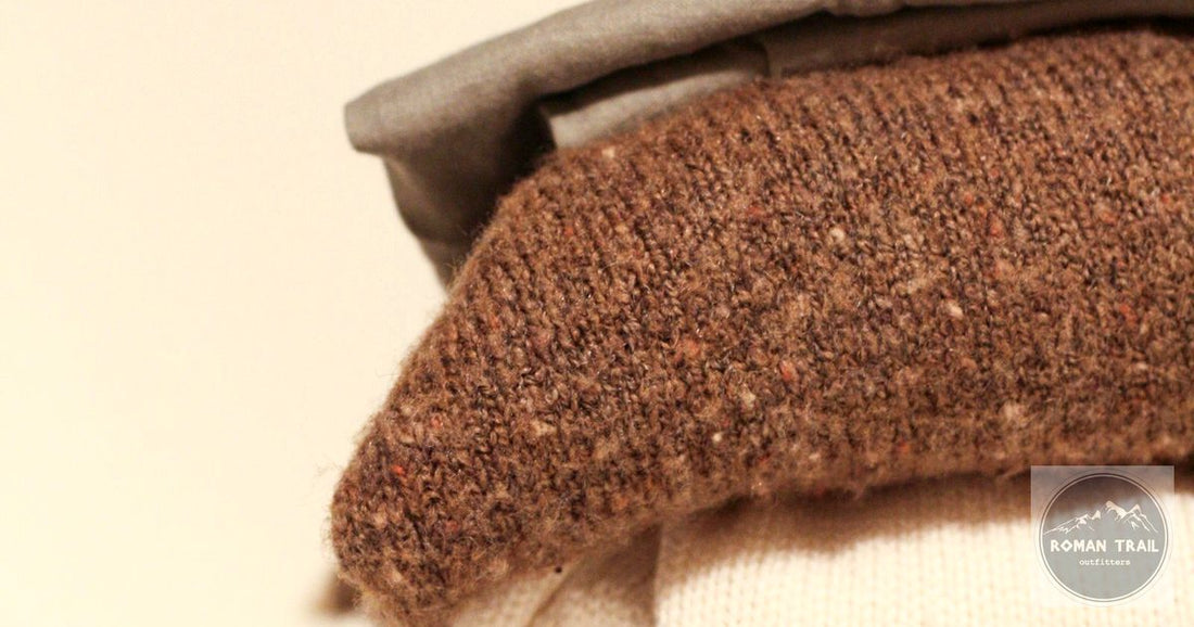 Folded warm-toned wool knitwear close-up, merino wool vs cotton for travel by Roman Trail Outfitters