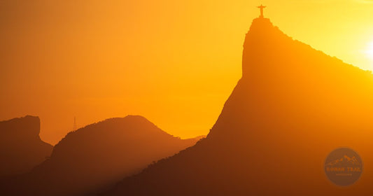 Christ the Redeemer statue silhouetted against a vivid orange sunset over Rio de Janeiro, women's Brazil packing list by Roman Trail Outfitters