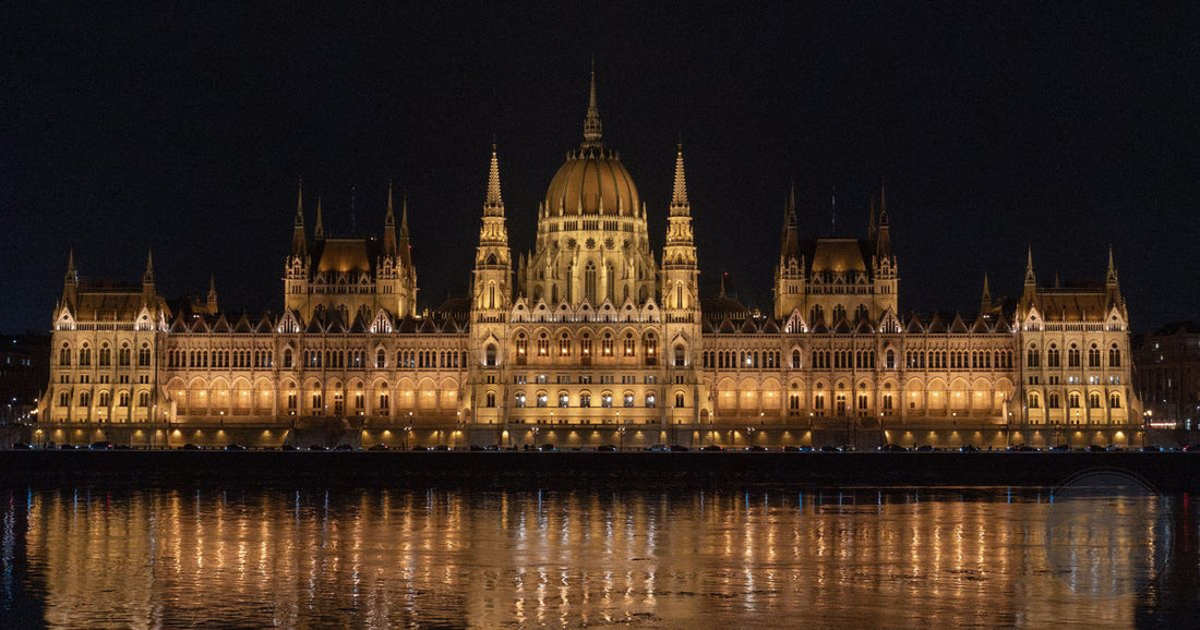 Hungarian Parliament building illuminated and reflected in the Danube River at night, women's Budapest packing list by Roman Trail Outfitters