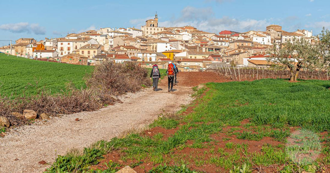 Camino de Santiago packing list for women, pilgrims walking toward a village in Spain