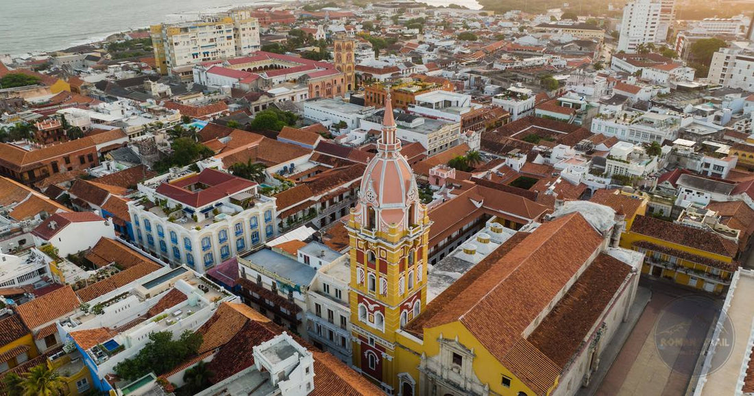 Aerial view of Cartagena's walled colonial city with the cathedral tower glowing warm gold at sunset, women's travel destination