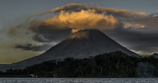 Arenal Volcano in Costa Rica with a glowing golden cloud plume above the rainforest canopy at dusk, women's travel destination