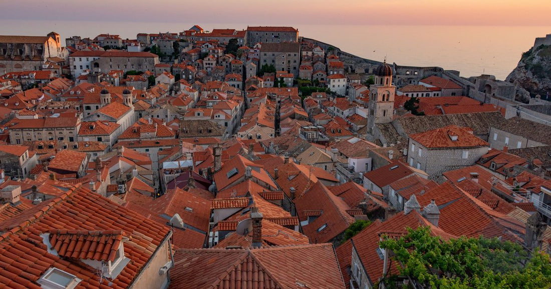 Aerial view of Dubrovnik's red rooftops and old city walls above the Adriatic at sunset, women's Croatia packing list by Roman Trail Outfitters