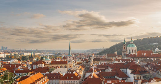 Prague Old Town red rooftops and church spires glowing warm gold at sunset, women's Czech Republic packing list by Roman Trail Outfitters