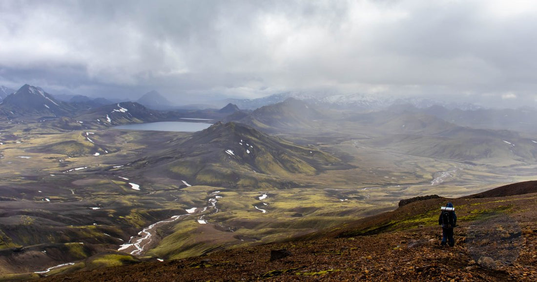 Hiker overlooking the colorful volcanic highlands of Landmannalaugar on the Laugavegur trail in Iceland - Roman Trail Outfitters Iceland packing list