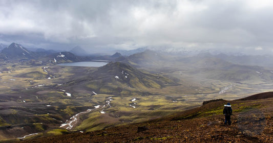 Hiker overlooking the colorful volcanic highlands of Landmannalaugar on the Laugavegur trail in Iceland - Roman Trail Outfitters Iceland packing list