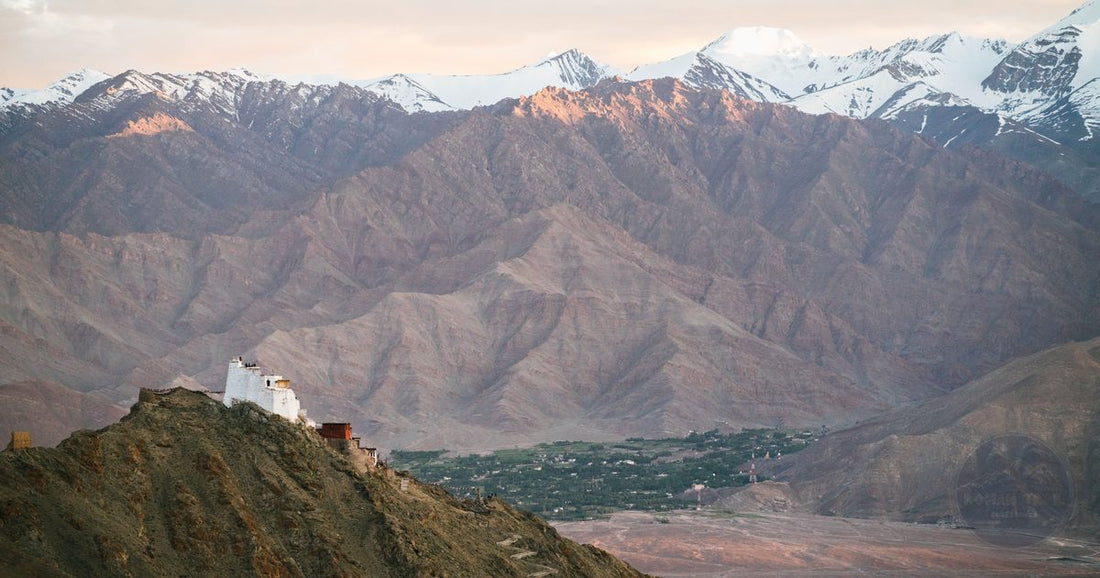 White Ladakh monastery on a mountain ridge above the Indus valley at golden hour, women's India packing list by Roman Trail Outfitters