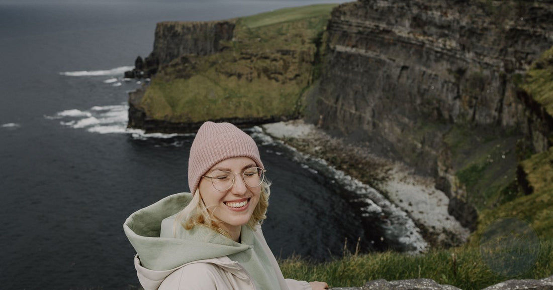 Woman hiking the Cliffs of Moher coastal path in Ireland wearing outdoor layers - Roman Trail Outfitters Ireland packing list