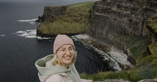 Woman hiking the Cliffs of Moher coastal path in Ireland wearing outdoor layers - Roman Trail Outfitters Ireland packing list
