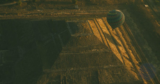 Aerial view of a hot air balloon casting long shadows over the Pyramid of the Sun at Teotihuacan, Mexico at golden hour, women's travel destination