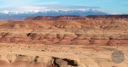 Snow-capped Atlas Mountains rising above red desert terrain in Morocco - Roman Trail Outfitters Morocco packing list