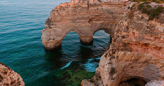 Algarve limestone sea arch at Praia da Marinha, Portugal glowing warm gold at sunset, women's travel destination