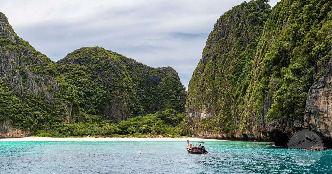 Turquoise Andaman water below limestone cliffs with a longtail boat in Phuket, Phuket packing list for women by Roman Trail Outfitters