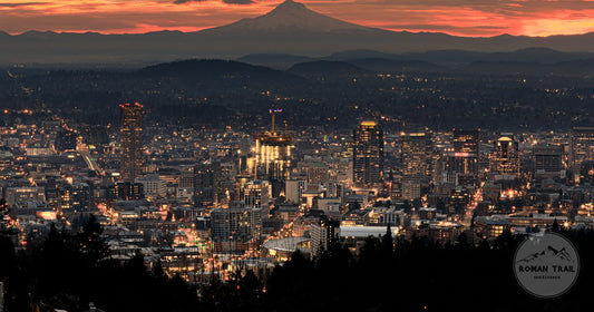 Downtown Portland lit at dusk with Mount Hood silhouetted against an orange sunset, Portland packing list for women by Roman Trail Outfitters