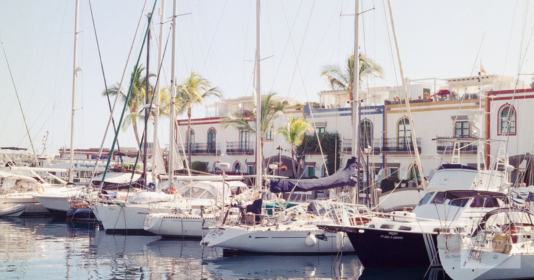 Colorful view of yachts docked at Puerto de Mogán marina in Spain, with palm trees and vibrant buildings