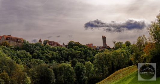 Scenic view of Rothenburg ob der Tauber's medieval skyline framed by lush autumn trees.