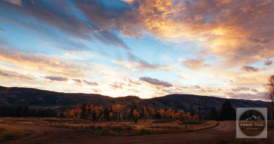 Sunset over the ranch country outside Steamboat Springs, a dirt road winding through autumn grass in the Yampa valley.
