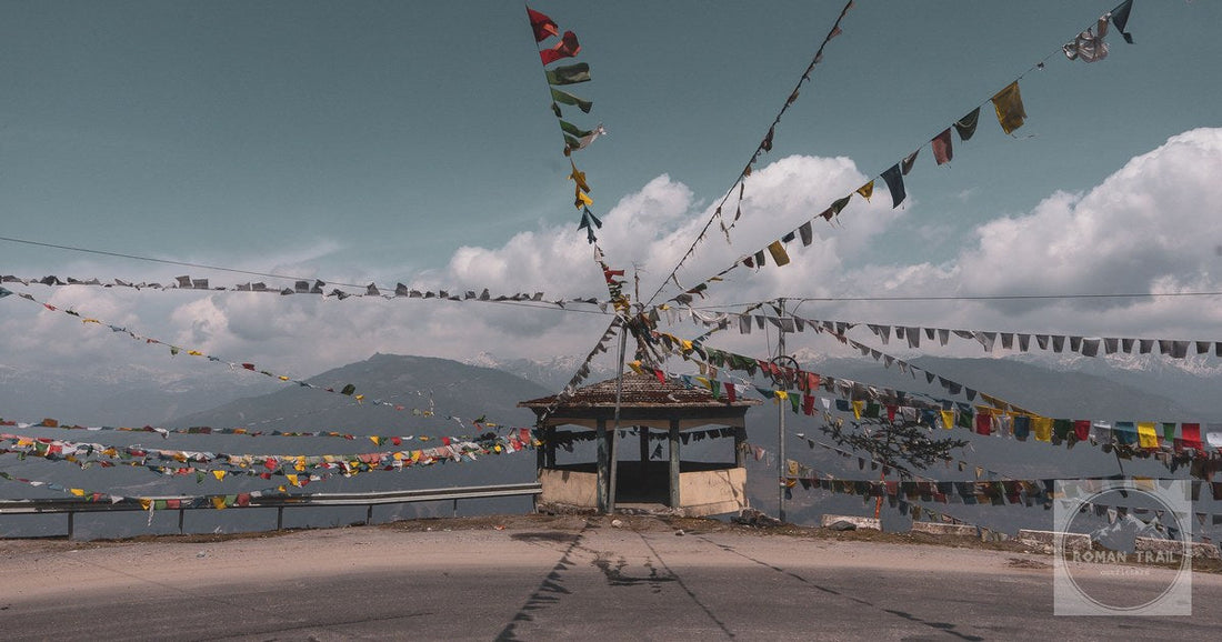 Colorful prayer flags on a mountain road in Tawang, offering a scenic Himalayan view.