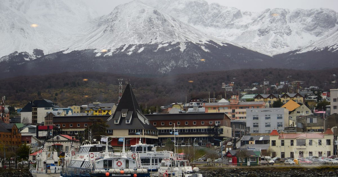 Boats in Ushuaia harbour below snow capped mountains at the end of Argentina, Ushuaia packing list for women by Roman Trail Outfitters